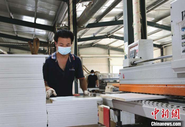(资料图)图为工人在菏泽市牡丹区九尘家居生产车间加工板材。　牡丹区供图